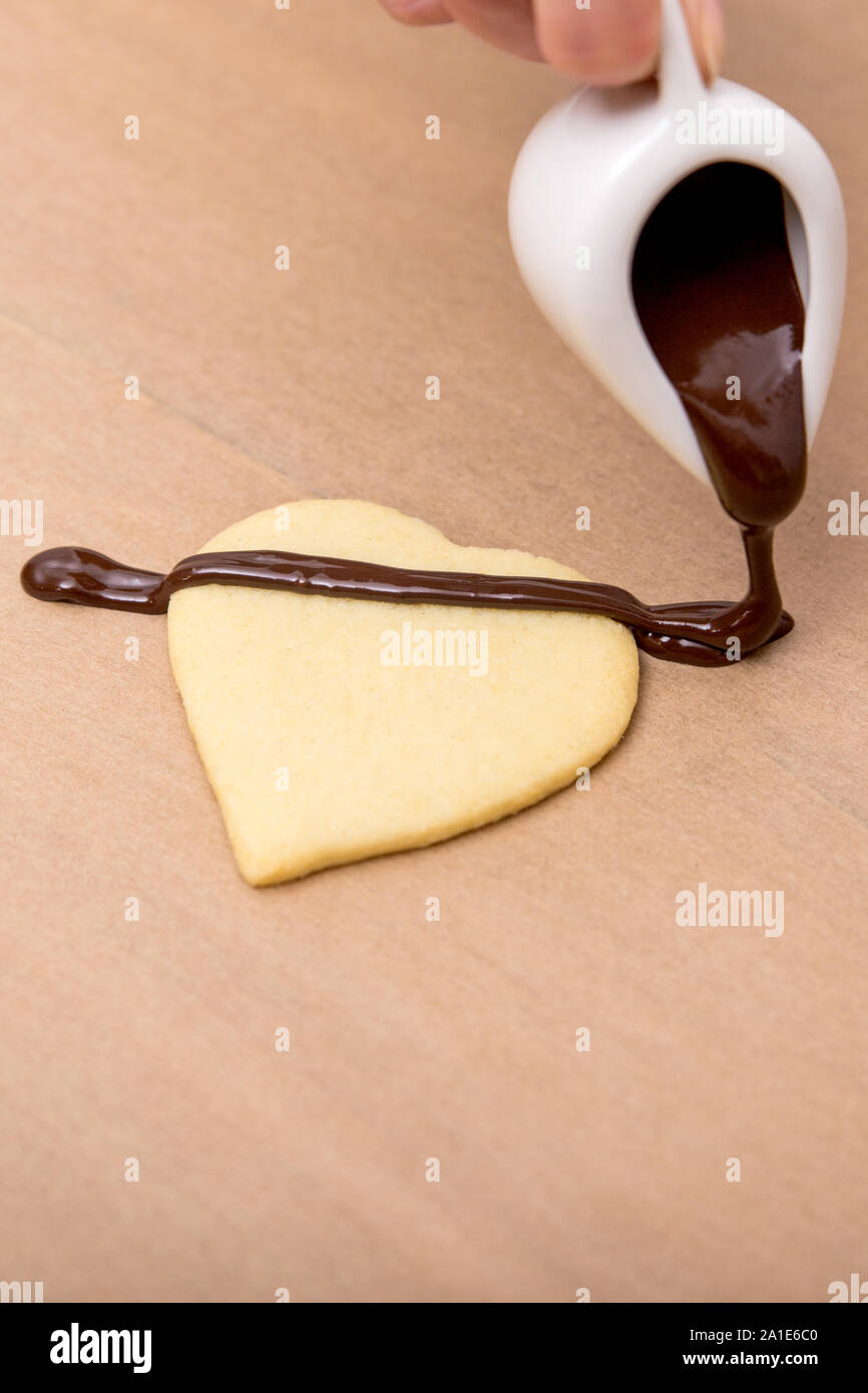 Forma di cuore cookie o biscotto con liquido di cioccolato fondente, vetratura copyspace Foto Stock