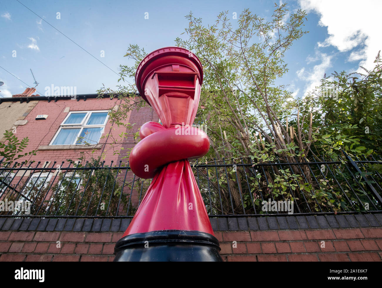 Un postino passeggiate passato un'arte lavoro intitolato Alphabetti Spaghett dall artista Alex Chinneck sulla strada Norborough in Sheffield, Yorkshire. Foto Stock
