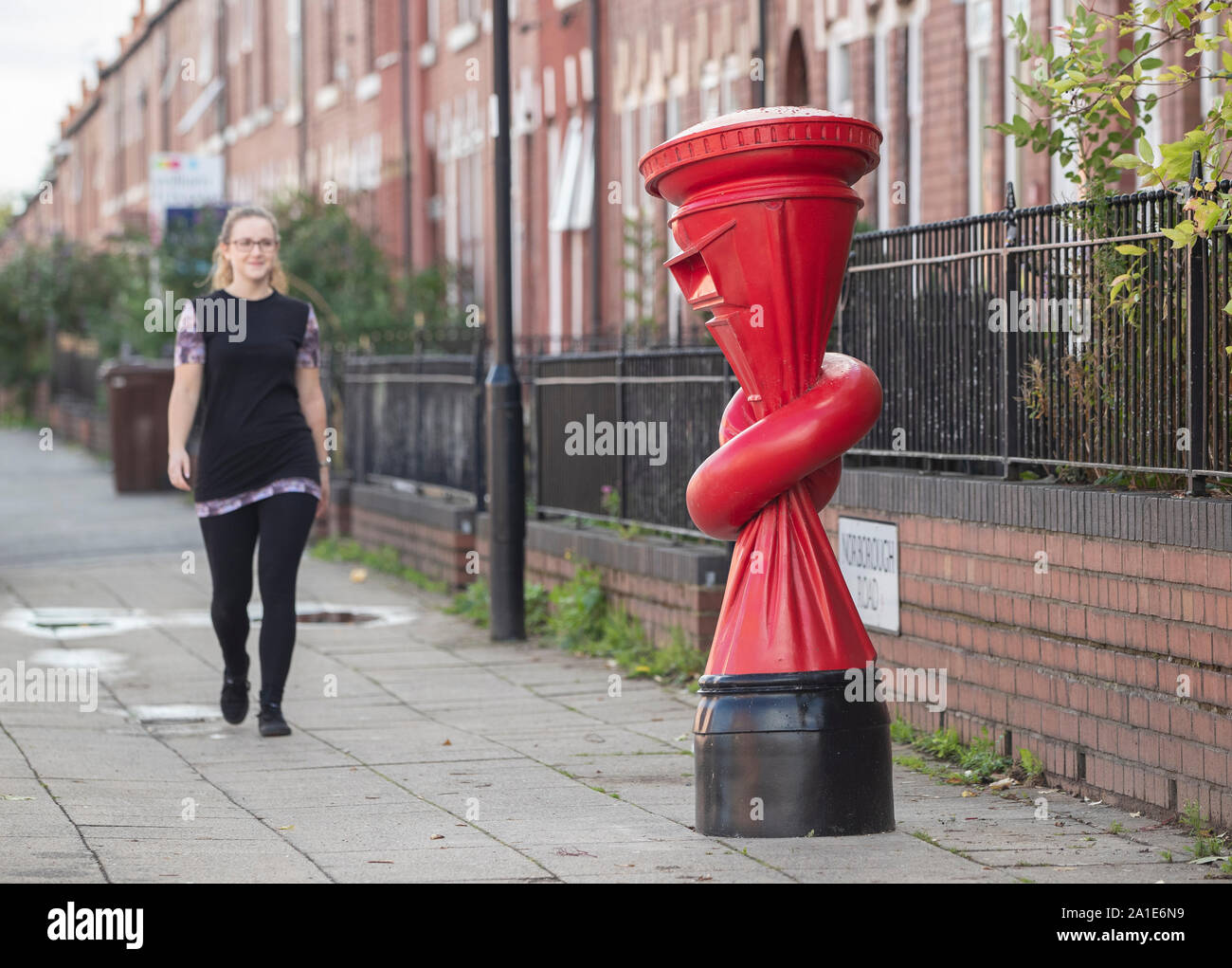 Una donna cammina passato un'arte lavoro intitolato Alphabetti Spaghett dall artista Alex Chinneck sulla strada Norborough in Sheffield, Yorkshire. Foto Stock