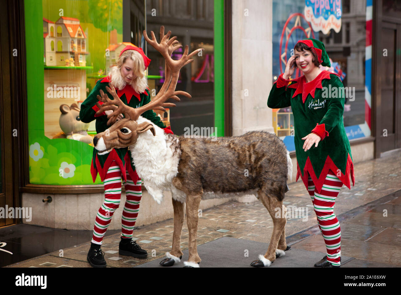A pochi fortunati i bambini hanno ottenuto un viaggio a Hamleys per il lancio del loro 10 giocattoli per Natale su Regent Street. Due elfi portano un animatronic renne fuori in strada per i bambini con cui giocare. Foto Stock