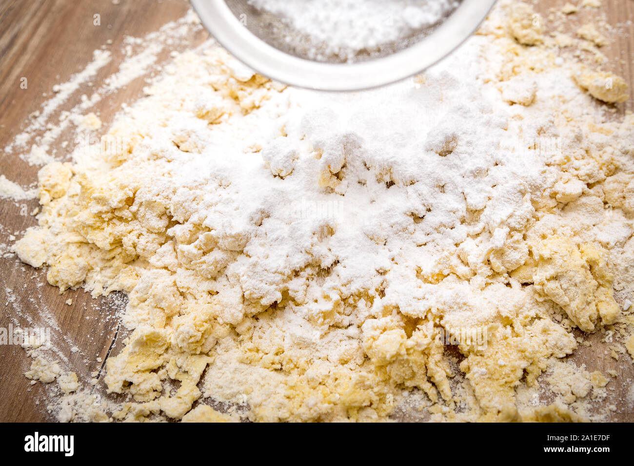 Lo zucchero in polvere di vagliatura su materie sbricioli o pasta biscotto, processo da forno Foto Stock