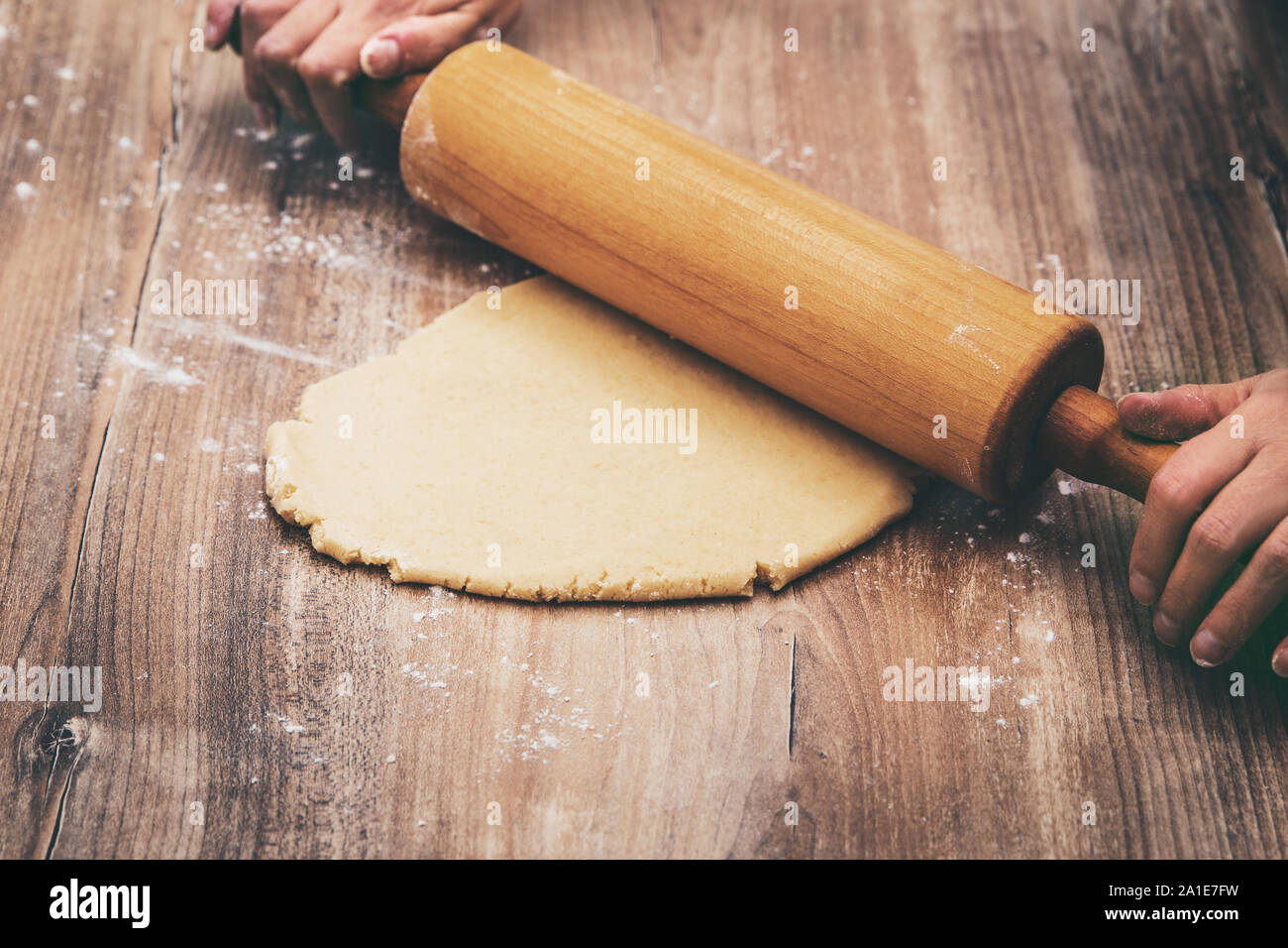 Donna ist grezzi di laminazione pasta biscotto con un matterello, il concetto di processo da forno Foto Stock