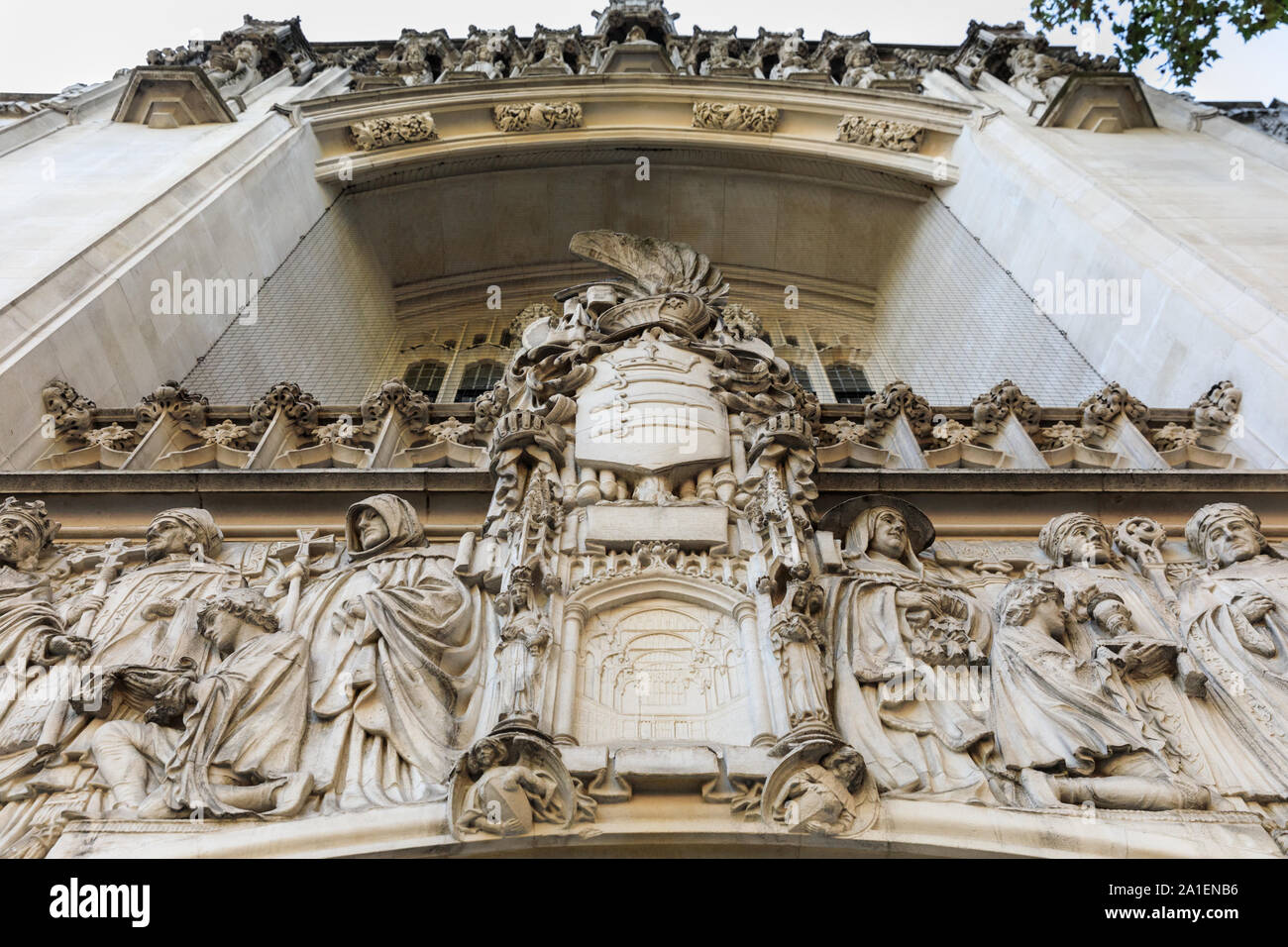 Visualizza in alto, la facciata esterna e muratura in pietra con statue ornamentali dello scultore Enrico Fehr, Regno Unito Corte Suprema, con la corte emblema, Londra Foto Stock