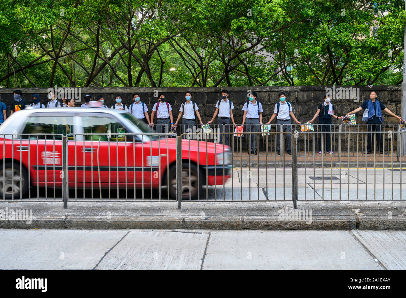 Morrison Hill, Wan Chai, Hong Kong, 26 settembre 2019. Decine di studenti di scuola superiore formata una catena umana e appeso banner e poster su Queens Rd West. Un taxi rigidi mediante la catena umana degli studenti di scuola superiore. Foto Stock