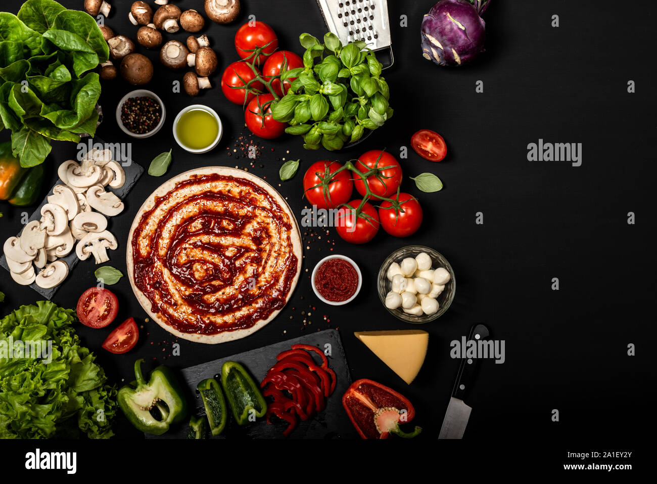 Composizione con impasto per pizza e delle materie prime per la cottura della pizza italiana. Vista dall'alto su uno sfondo nero Foto Stock