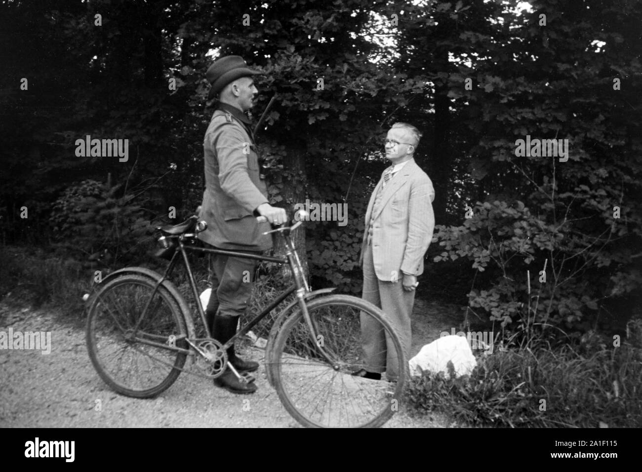 Ein Förster bei seinem Fahrrad unterhält sich mit einem älteren Herrn am Wegesrand, Deutschland 1939. Una foresta operaio con la sua bicicletta a parlare con un anziano uomo che ha incontrato sul suo cammino, Germania 1939. Foto Stock