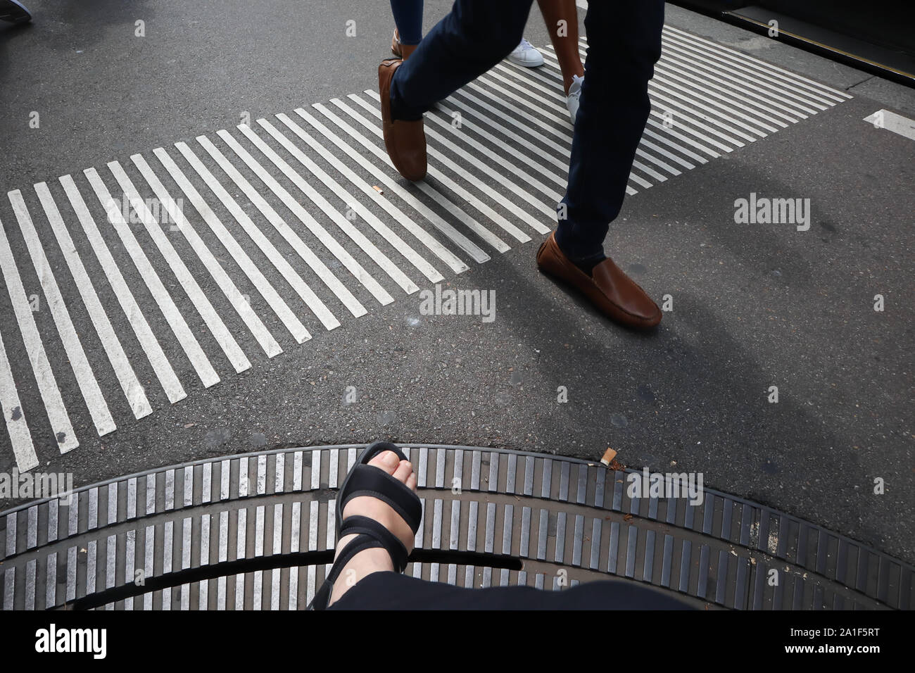 Paio di cittadini in giacca attraversando la strada a un attraversamento pedonale e del piede femminile su chiusino, zebra crossing Foto Stock