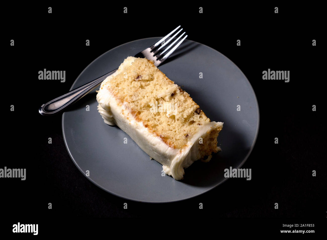 Spessa fetta di crema italiana la torta su blu-grigio piattino con forcella su sfondo scuro Foto Stock