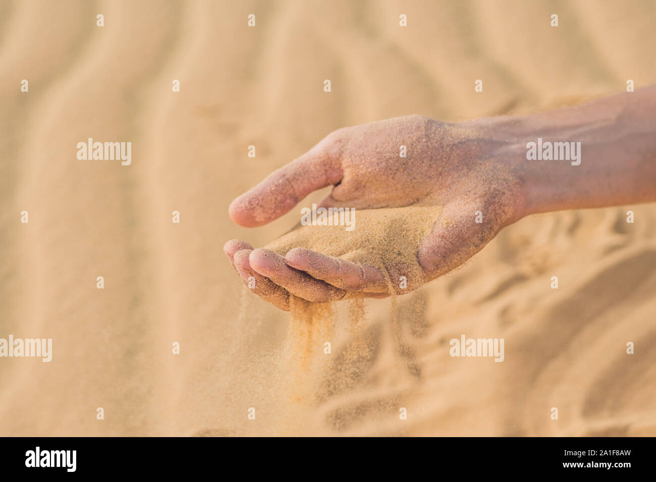 Deserto di sabbia, soffi attraverso le dita di una mano di un uomo. Foto Stock