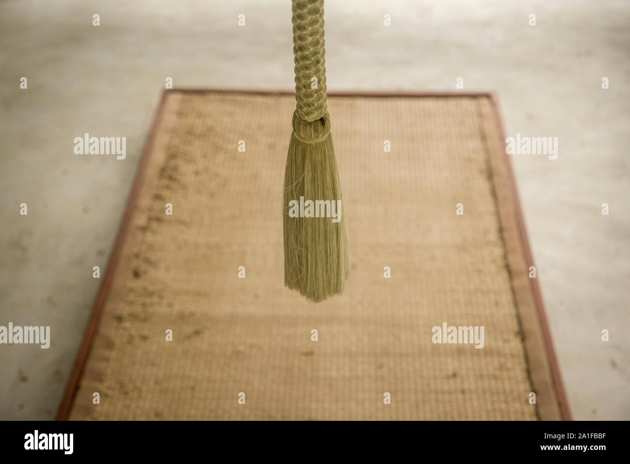 BellÂ buddista di corda e la meditazione tappetino sul pavimento grigio Foto Stock
