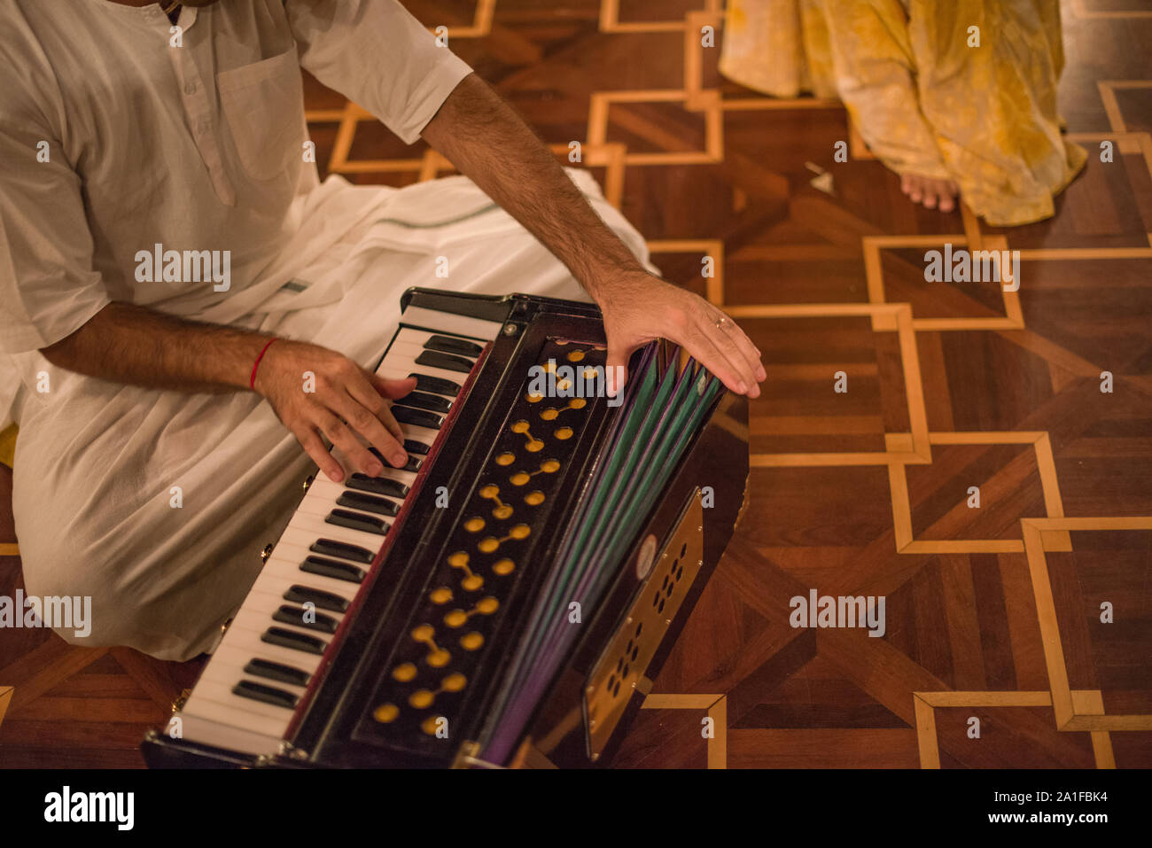 Hare Krishna devoto giocando Bhakti Harmonium sul pianale in legno Foto Stock