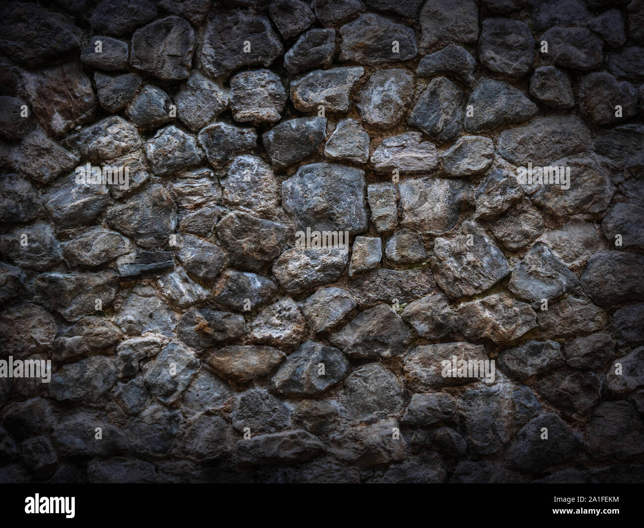 Muro di pietra di dark grossolana con ciottoli vignette Foto Stock