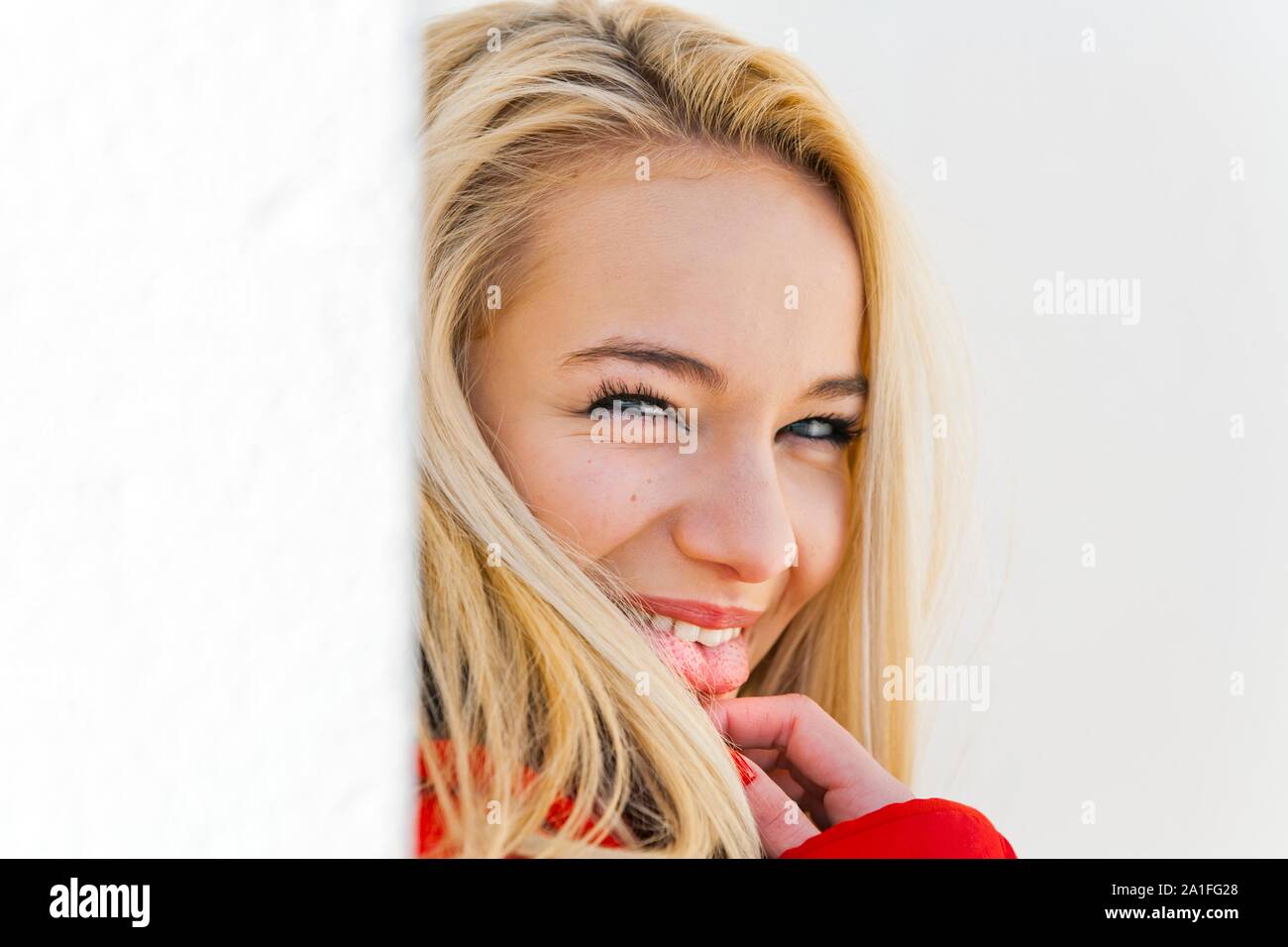 Eyeshot ritratto biondo lingua esposta recitazione fingere fingere di fingere di timido timido flirtare guardando la fotocamera sopra la spalla occhi contatto visivo teaser gioioso Foto Stock