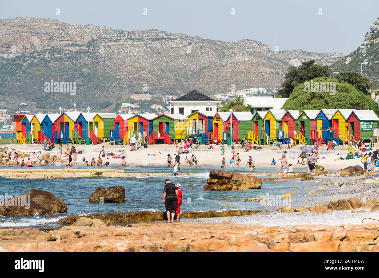Cabine sulla spiaggia, a St James,Cape Peninsula, Cape Town, Sud Africa,luminose e colorate, con la folla di persone o beachgoers godendo il tempo libero in Estate Foto Stock