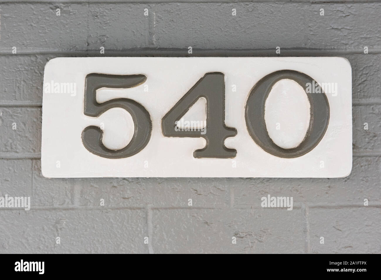 Edificio numero cinque cento quaranta (540) su una lapide bianca contro il grigio di un muro di mattoni Foto Stock
