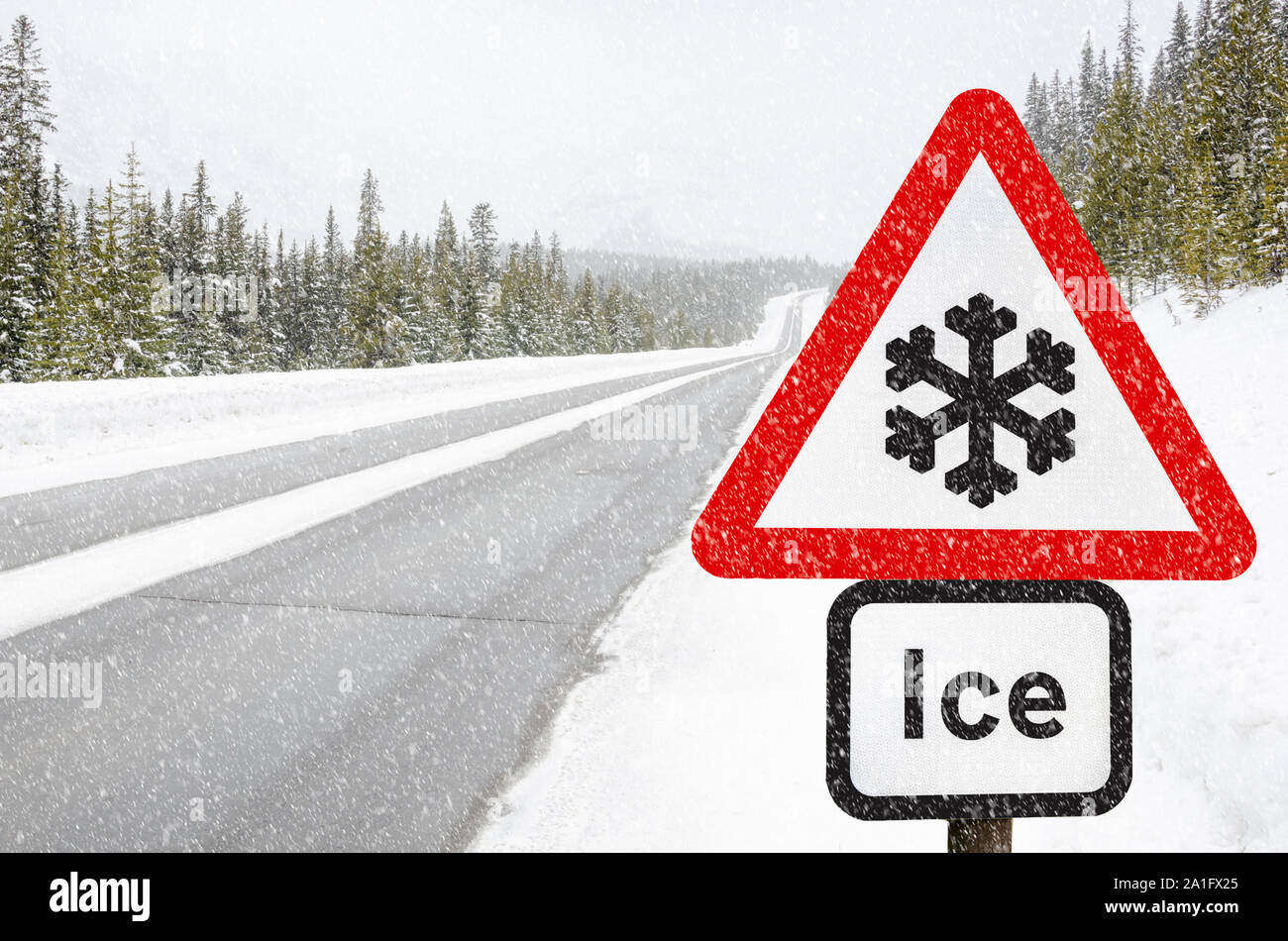 Segno di traffico lungo una strada di montagna avvertimento contro condizioni di gelo durante una nevicata Foto Stock