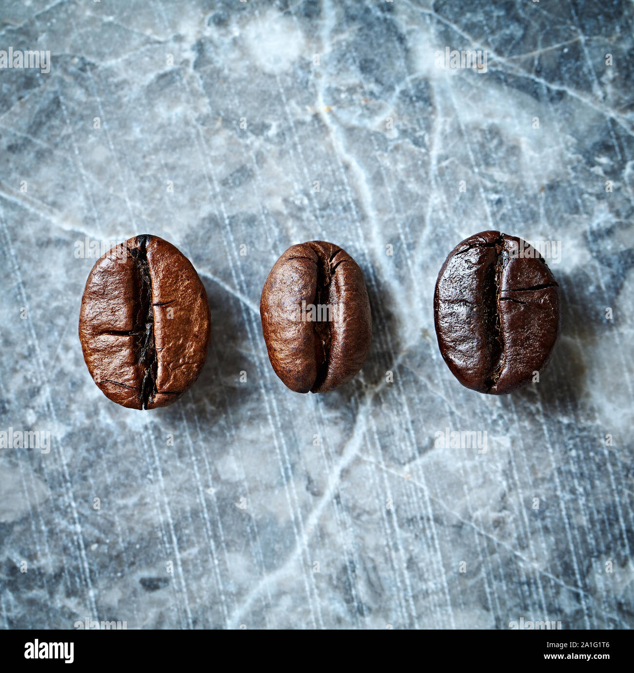 Tre tipi di chicchi di caffè su un sfondo marmo. Dark i chicchi di caffè rustico sfondo. Immagine simbolica. Close up. Vista dall'alto. Foto Stock