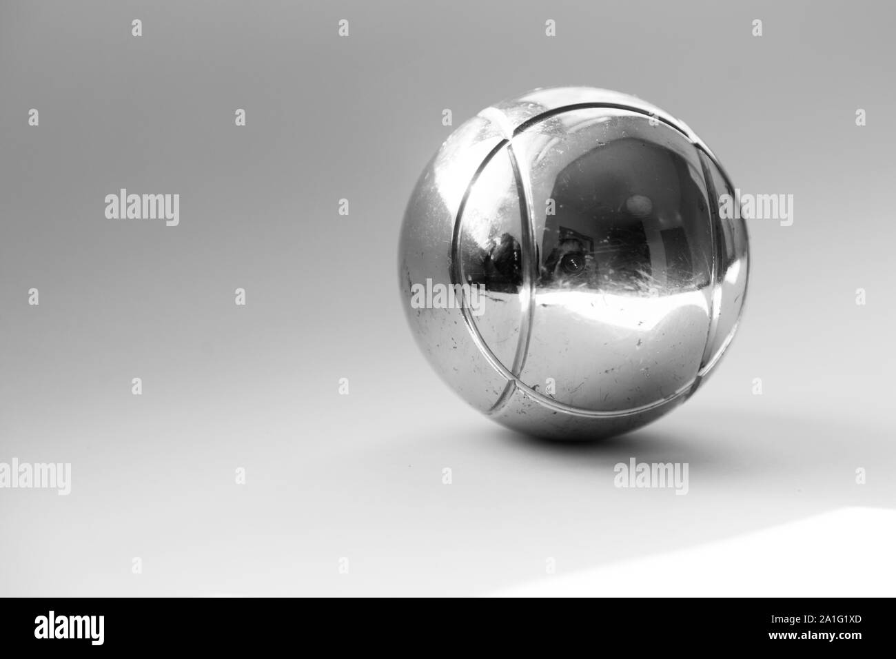 Un argento Boule globe giace su uno sfondo chiaro con riflessi fantasma Foto Stock