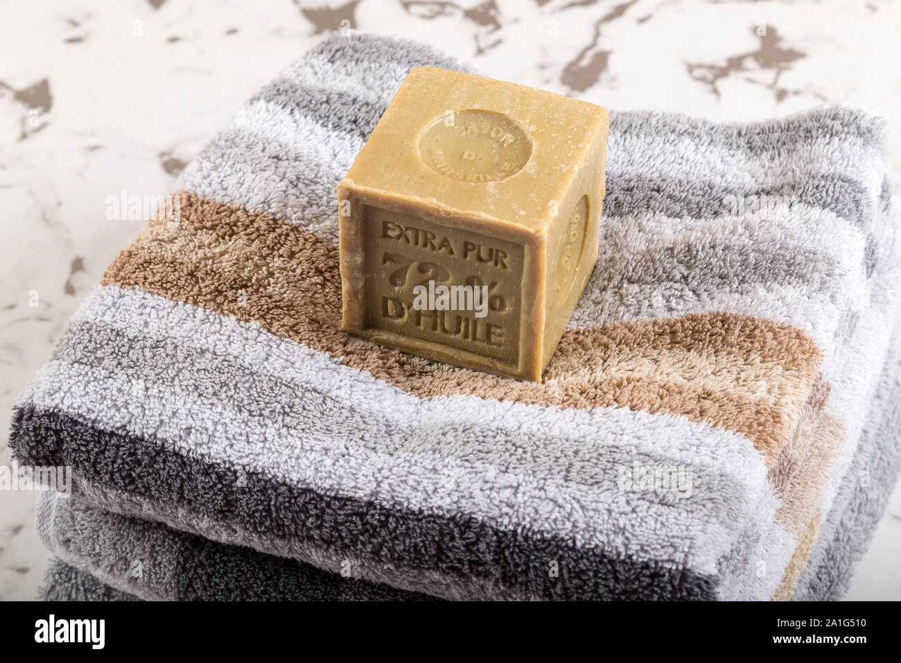 Organici di pezzo di sapone su una pila di asciugamani su marmo metropolitana. Umore per premium spa wellness hotel o naturopatia. Foto Stock