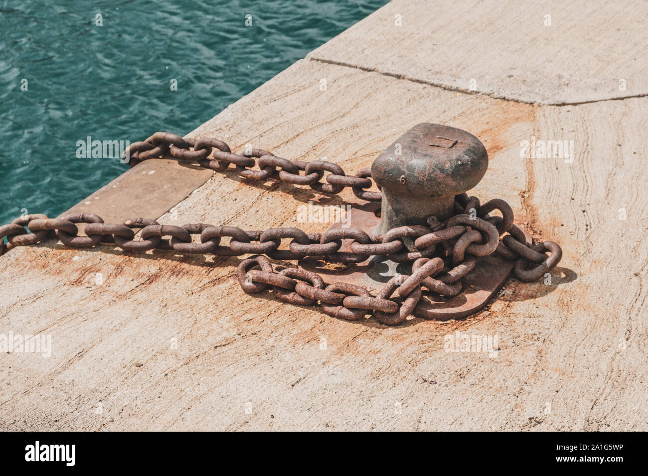 Rusty catena sul posto barca bollard sul dock closeup - nave ancorata sul porto Foto Stock