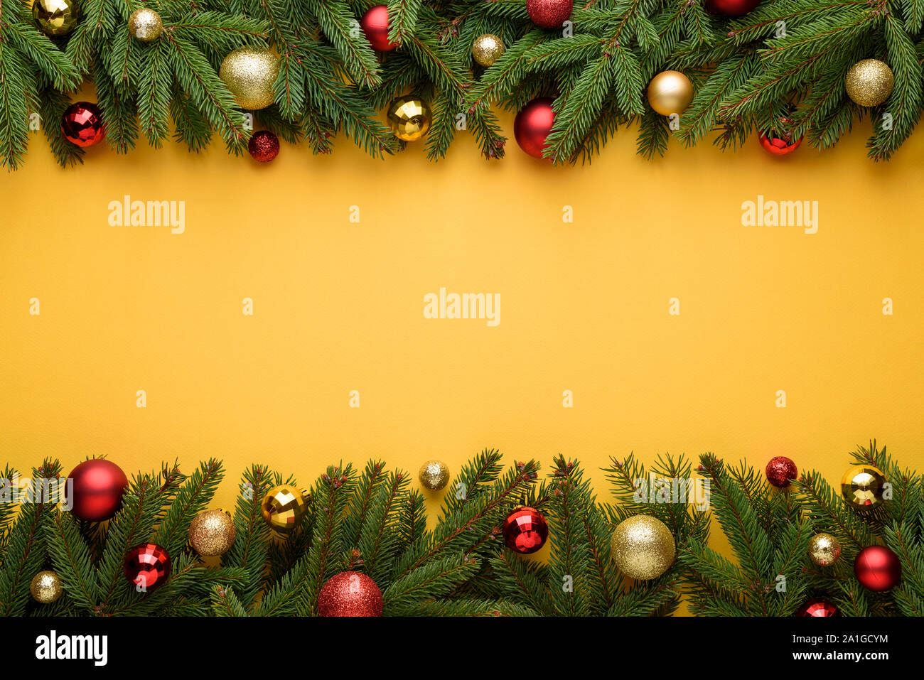 Cornice decorativa di palle di Natale e rami di abete. Sfondo giallo di Buon Natale e Anno Nuovo design. Copia dello spazio per le promozioni e congra Foto Stock