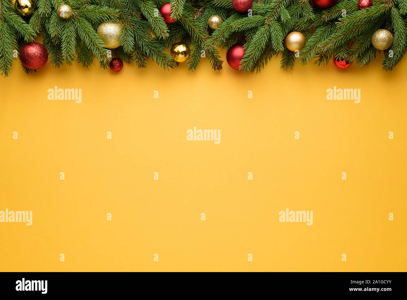 Cornice decorativa di palle di Natale e rami di abete. Sfondo giallo per Natale e Anno Nuovo design. Copia dello spazio per le promozioni, la pubblicità e la Foto Stock