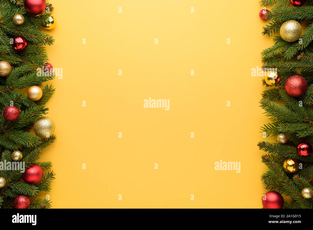 Cornice decorativa di palle di Natale e rami di abete. Sfondo giallo di Buon Natale e Anno Nuovo design. Copia dello spazio per le promozioni e congr Foto Stock