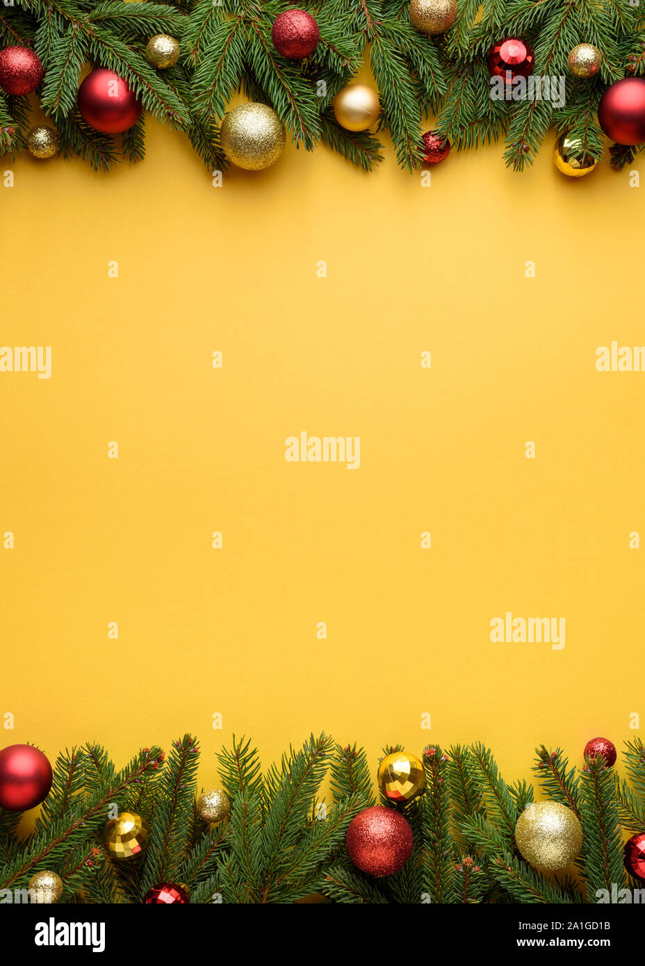 Cornice decorativa di rami di abeti e palle di Natale. Sfondo giallo per Natale design. Copia dello spazio per le promozioni e congratulazioni testo Foto Stock