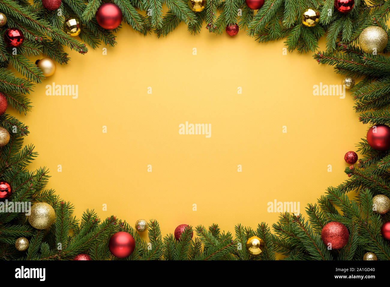 Cornice ovale di palle di Natale e rami di abete. Sfondo giallo per Natale e Anno Nuovo design. Copia dello spazio per le promozioni, la pubblicità e congra Foto Stock