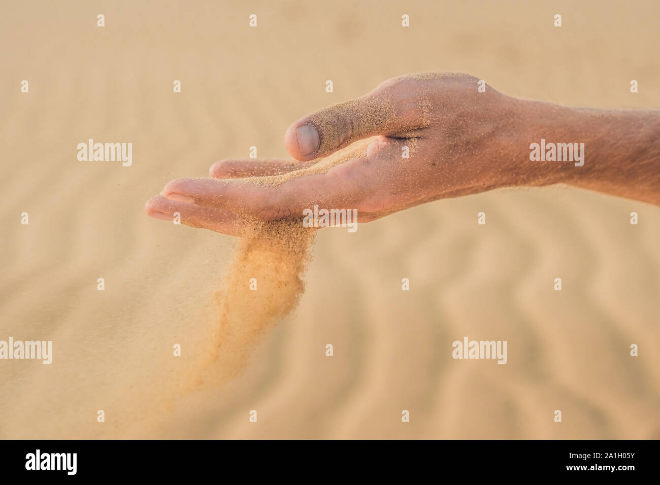 Deserto di sabbia, soffi attraverso le dita di una mano di un uomo. Foto Stock