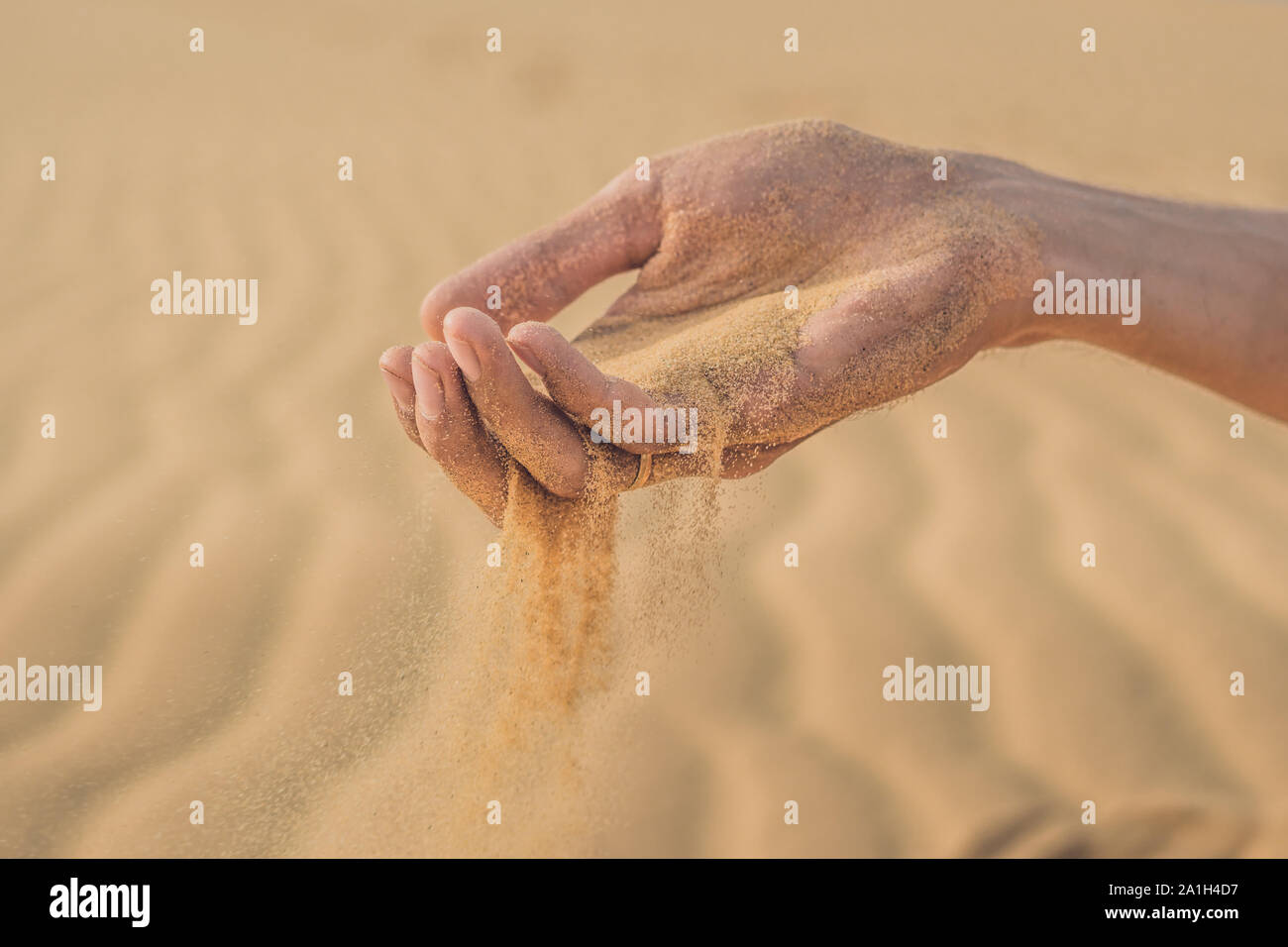 Deserto di sabbia, soffi attraverso le dita di una mano di un uomo. Foto Stock