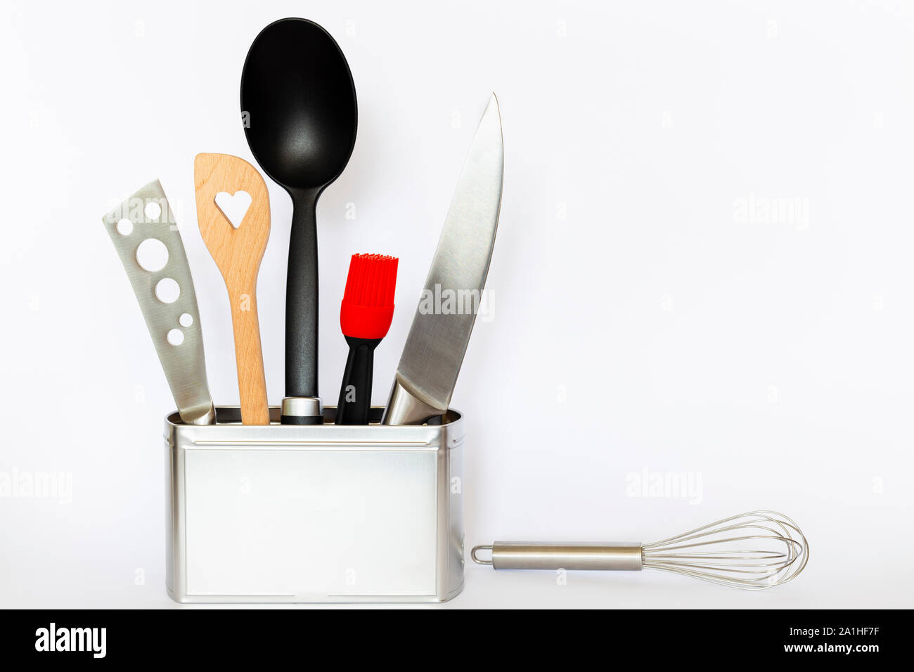 Assortimento di stoviglie e utensili da cucina in un quadrato di colore argento scatola di metallo con copia spazio su sfondo bianco Foto Stock