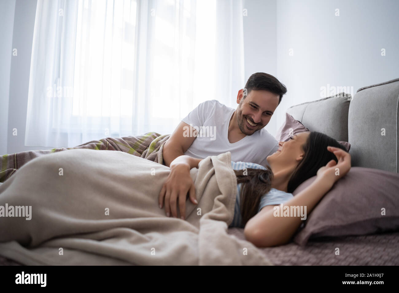 Giovane coppia felice nel letto la mattina. Foto Stock