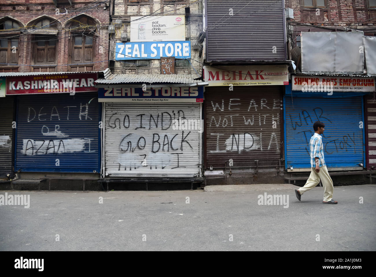 Un uomo cammina passato negozi chiusi durante le restrizioni in Srinagar.Dopo la revoca dell'articolo 370 che conferisce lo status speciale di Jammu e Kashmir, le autorità statali hanno imposto restrizioni in Kashmir per prevenire le proteste. Foto Stock