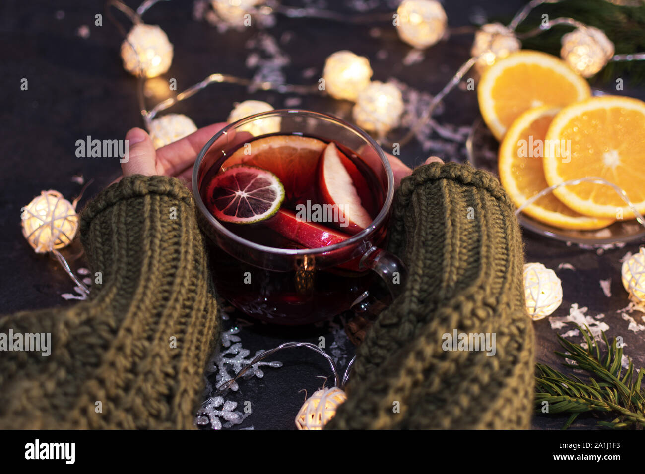 Donna che mantiene un bicchiere di vetro di Natale caldo vin brulé in mani, primo piano. Inverno bevanda di natale. Foto Stock