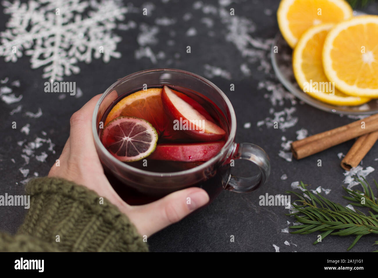 Donna che mantiene un bicchiere di vetro di Natale caldo vin brulé in mani, primo piano. Inverno bevanda di natale. Foto Stock