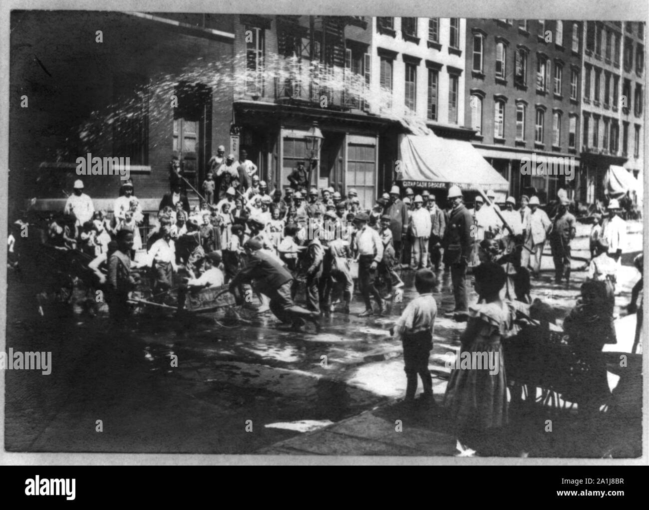 Bambini N.Y.C. in tempo caldo, giocando in spray di idrante di fuoco, poliziotti in attesa Foto Stock