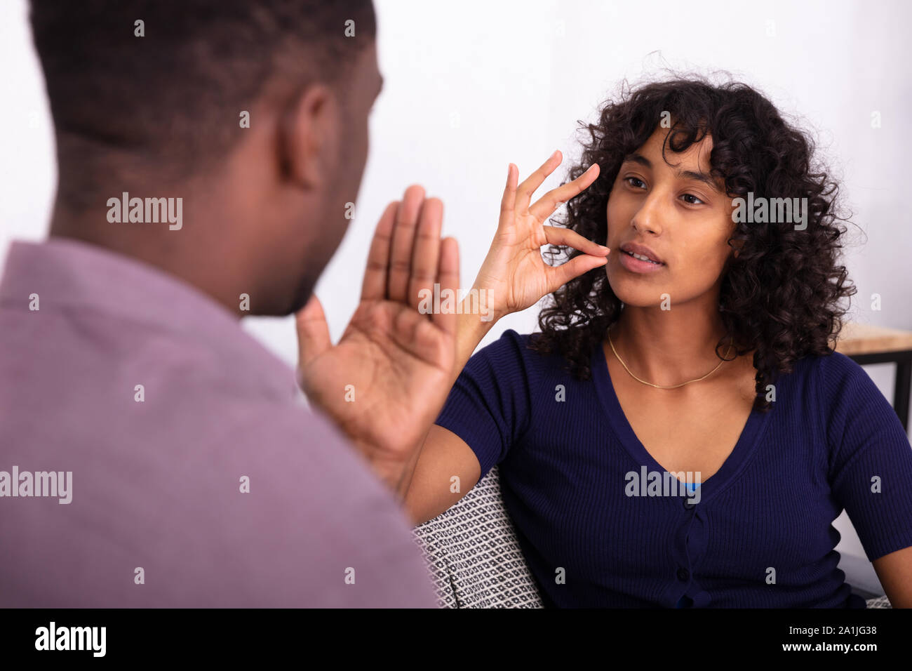 L uomo e la donna in comunicazione con le lingue gestuali seduto sul divano Foto Stock