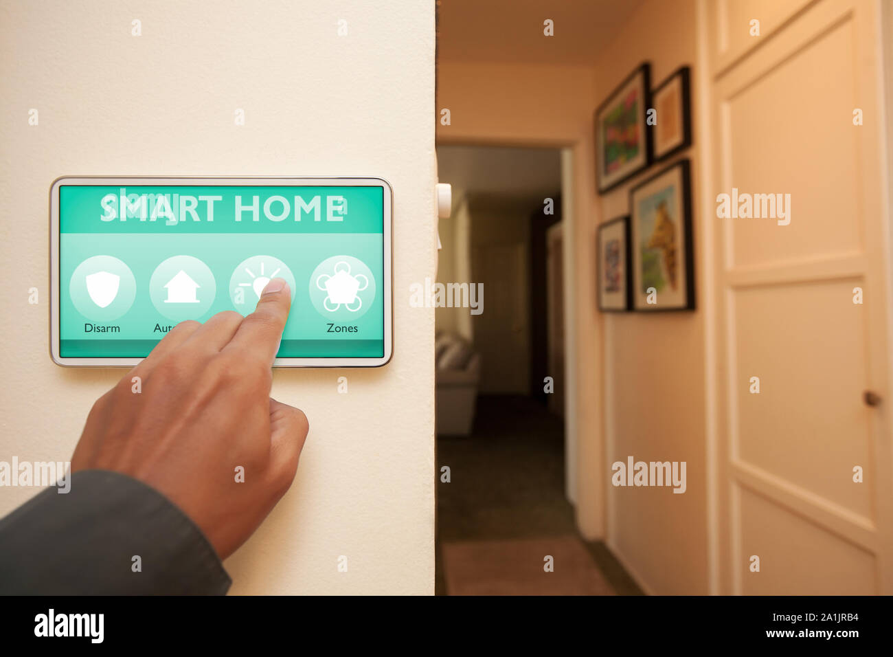 Proprietario di casa utilizzando la home automation control center apparecchio per accendere le luci all'interno della casa. Foto Stock