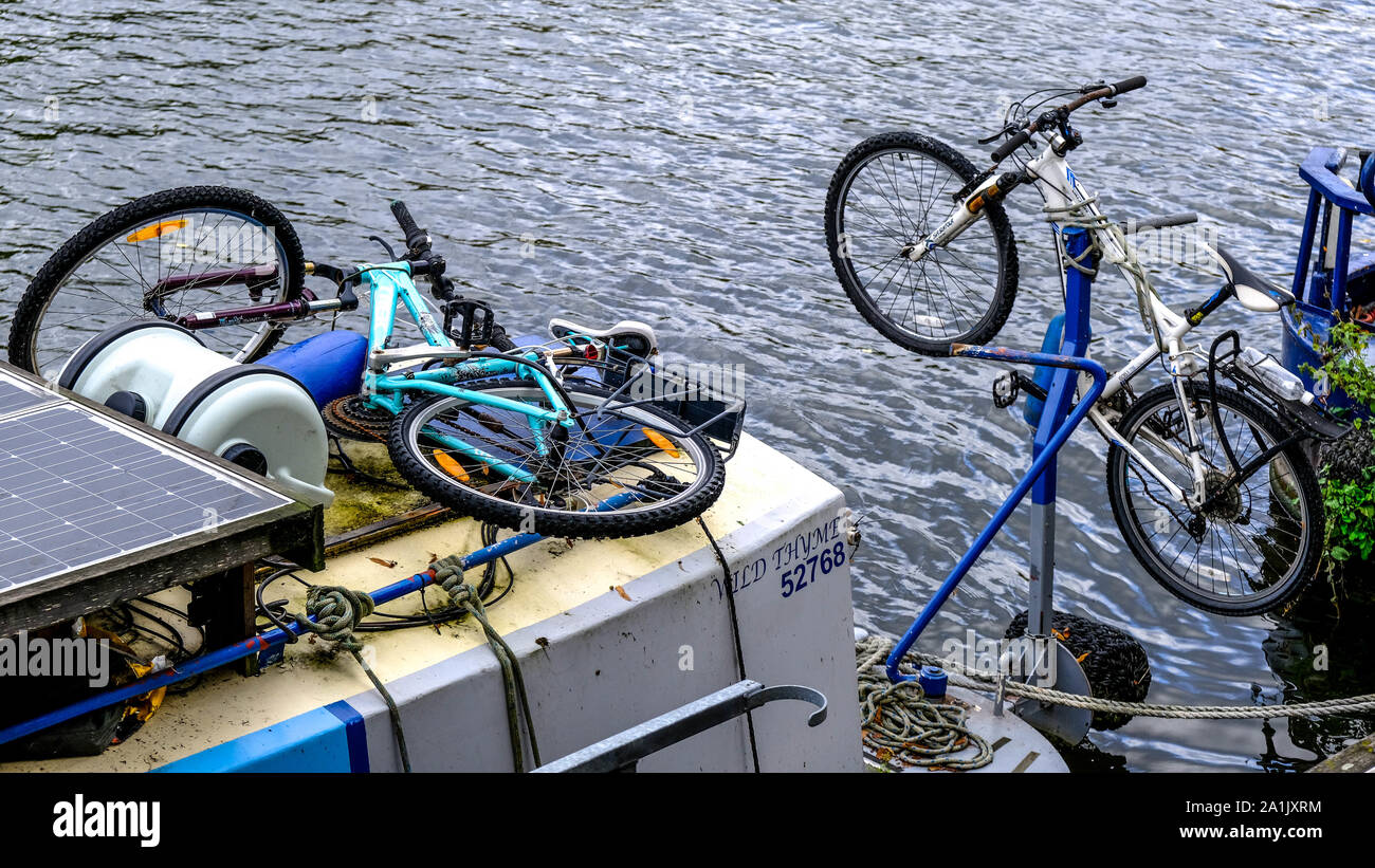 Biciclette o moto Push legati al fiume case galleggianti sul fiume Tamigi, Londra Foto Stock