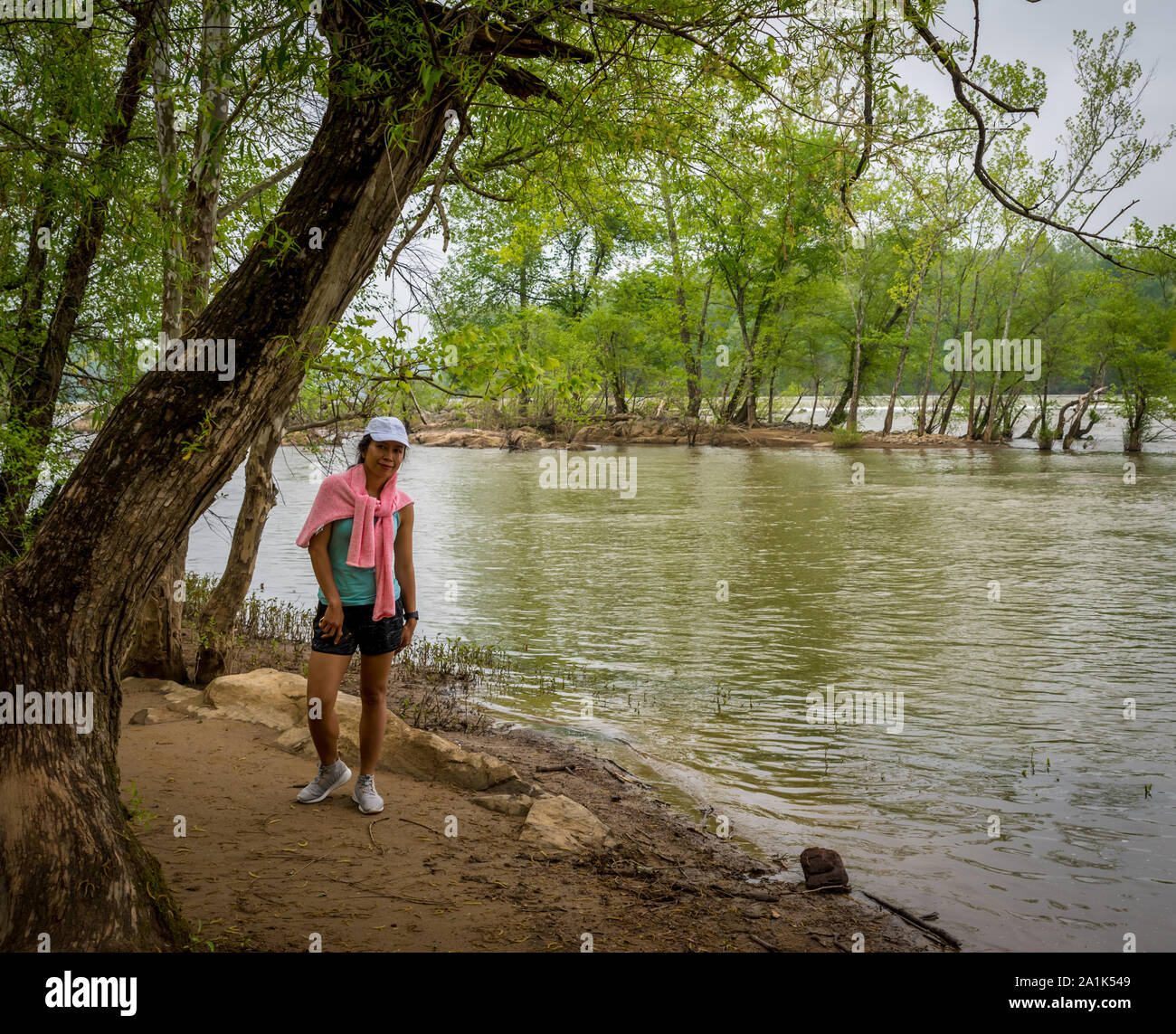 Medioevo donna con rosa maglione in piedi dal fiume sul sentiero nel Parco Nazionale Foto Stock