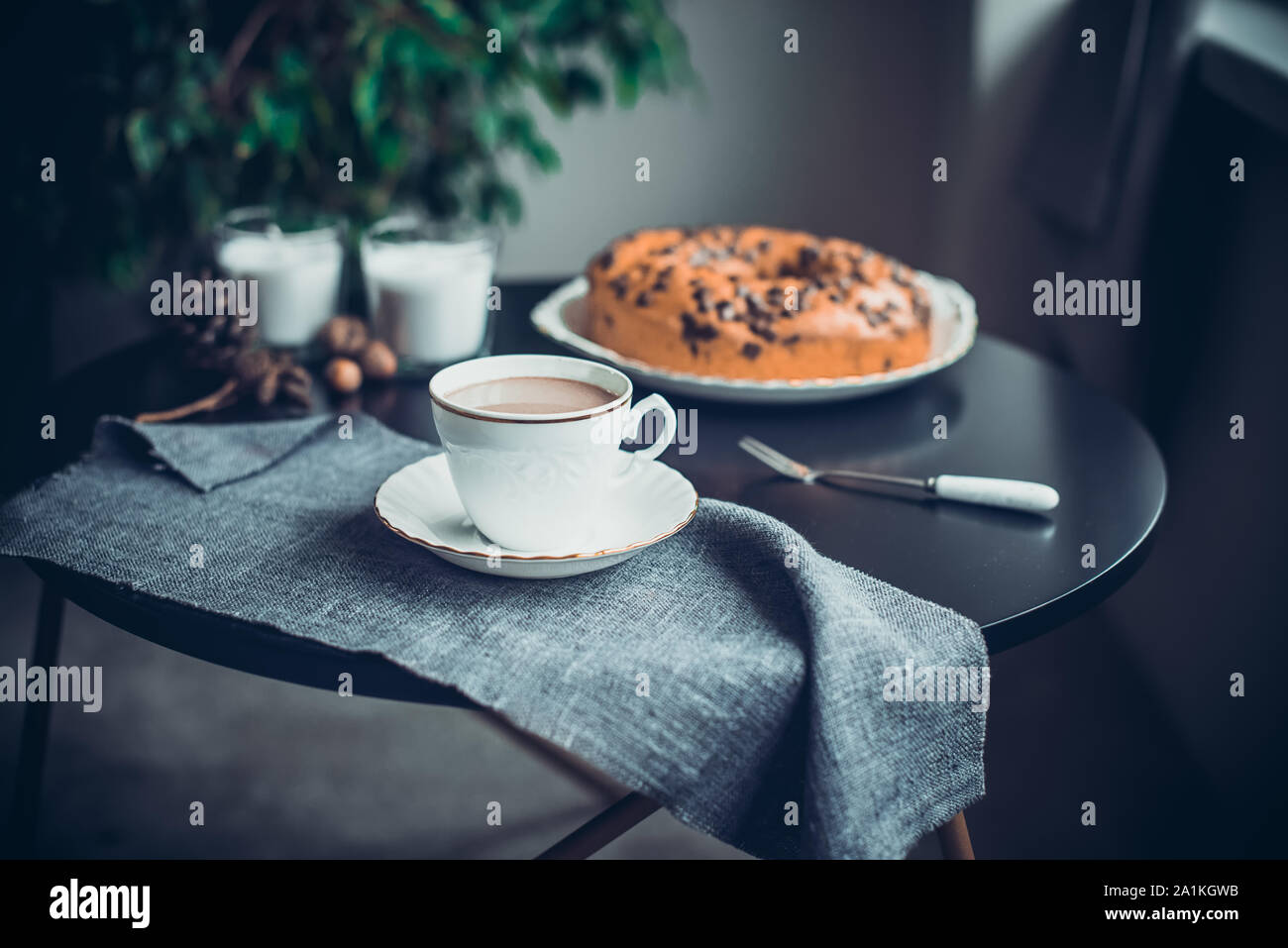 Tazza di caffè o di cacao, torta, candele bianche e coni naturale, decor i dadi sul tavolo scuro. Accogliente atmosfera di casa. Mattina in noir stile Nordic. Hy Foto Stock