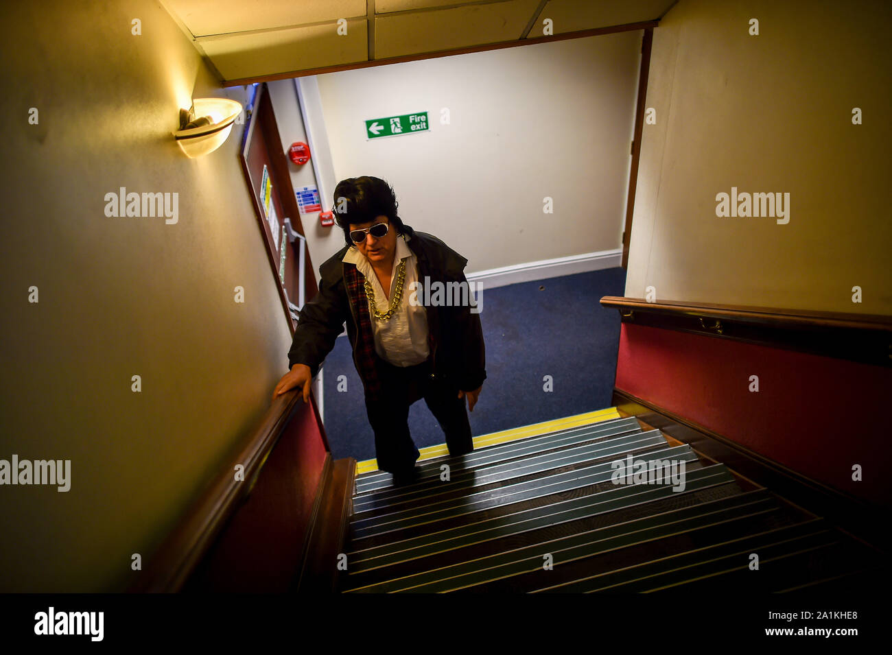 Un uomo vestito come Elvis si arrampica su una rampa di scale all'interno del Grand Pavillion all annuale Porthcawl festival di Elvis in Galles del Sud. La manifestazione richiama migliaia di fan di Elvis alla Welsh cittadina balneare per celebrare il Re del Rock and Roll'. Foto Stock