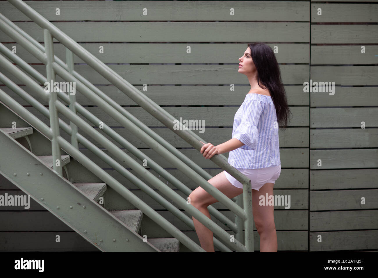 Bella giovane donna salendo le scale industriali sui backstreet Foto Stock