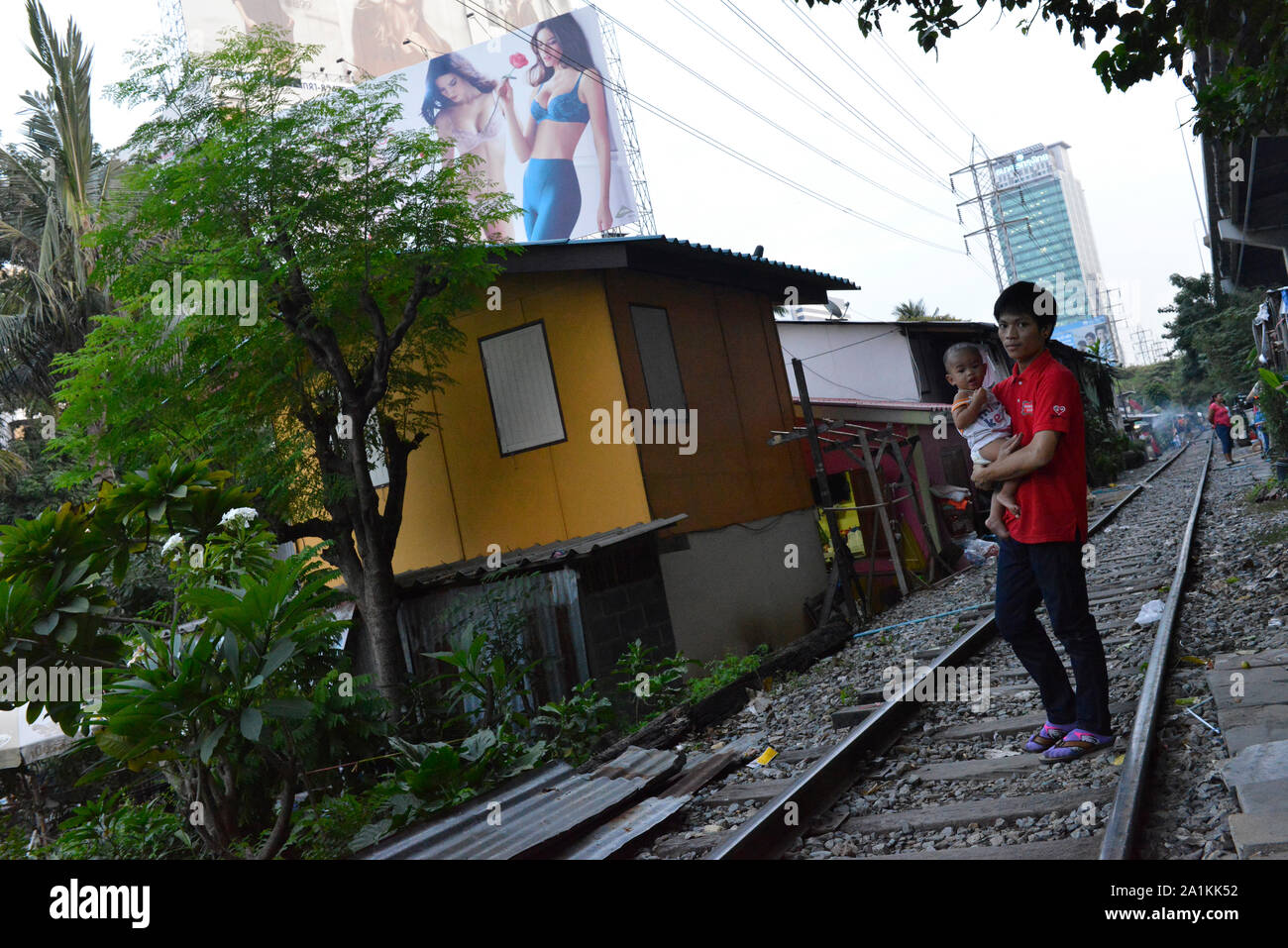 Un padre sta camminando con il suo figlio nelle sue braccia sul tracciato ferroviario nella baraccopoli di Bangkok, Thailandia, Sud-est asiatico. Foto Stock