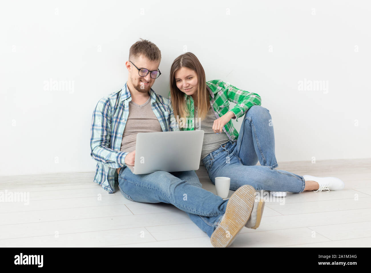 Affascinante giovane donna e un uomo sorridente sta guardando i negozi online utilizzando un computer portatile per acquistare impianti idraulici in un nuovo appartamento. Inaugurazione della casa nuova e il concetto di riparazione. Foto Stock