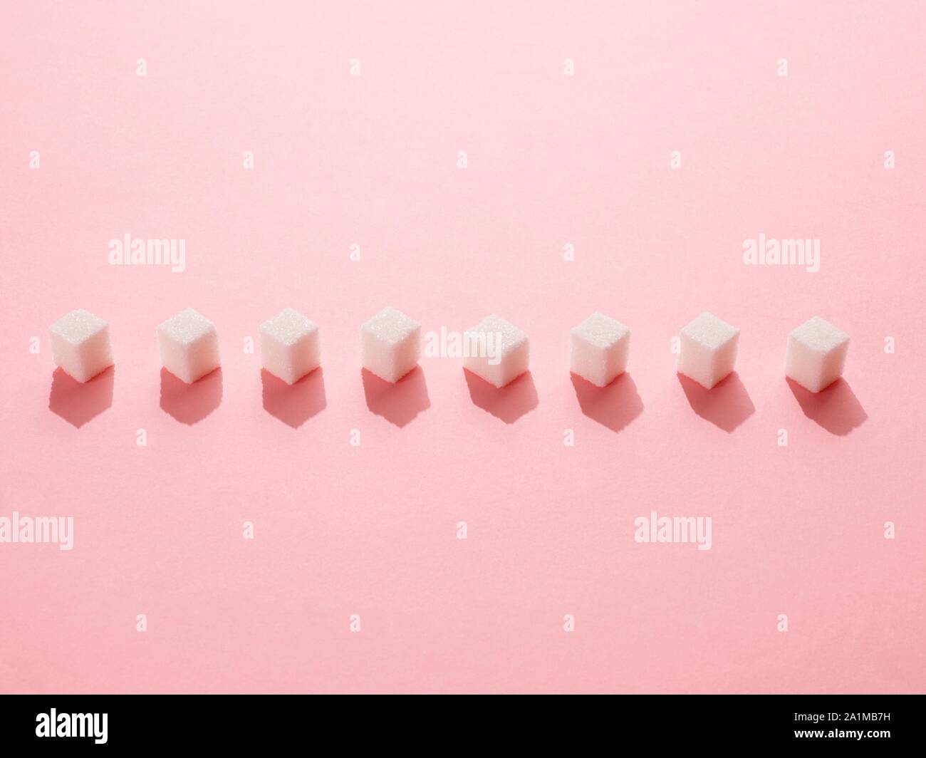 Zollette di zucchero su sfondo rosa. Foto Stock