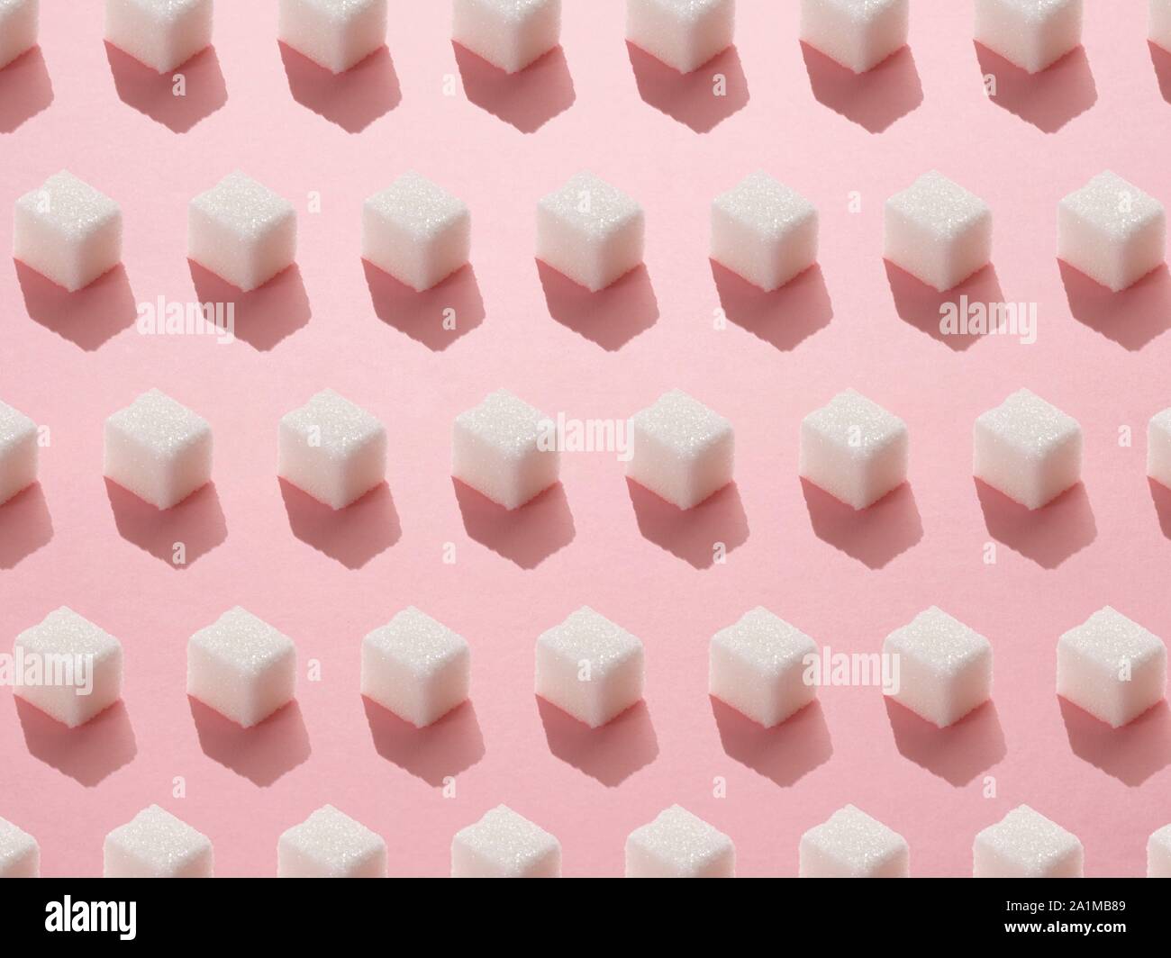Zollette di zucchero su sfondo rosa. Foto Stock