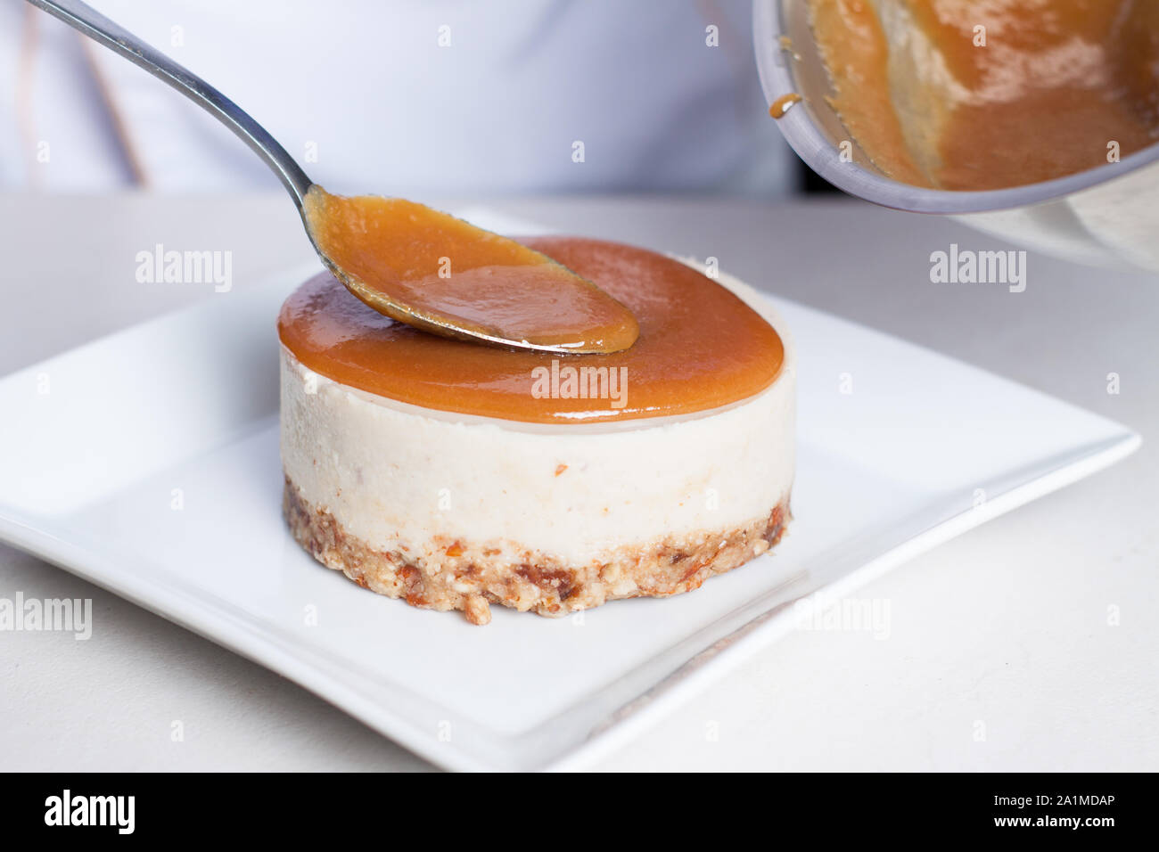 Preparazione delle materie vegan cheesecake con sirup di caramello e frutti di bosco freschi Foto Stock