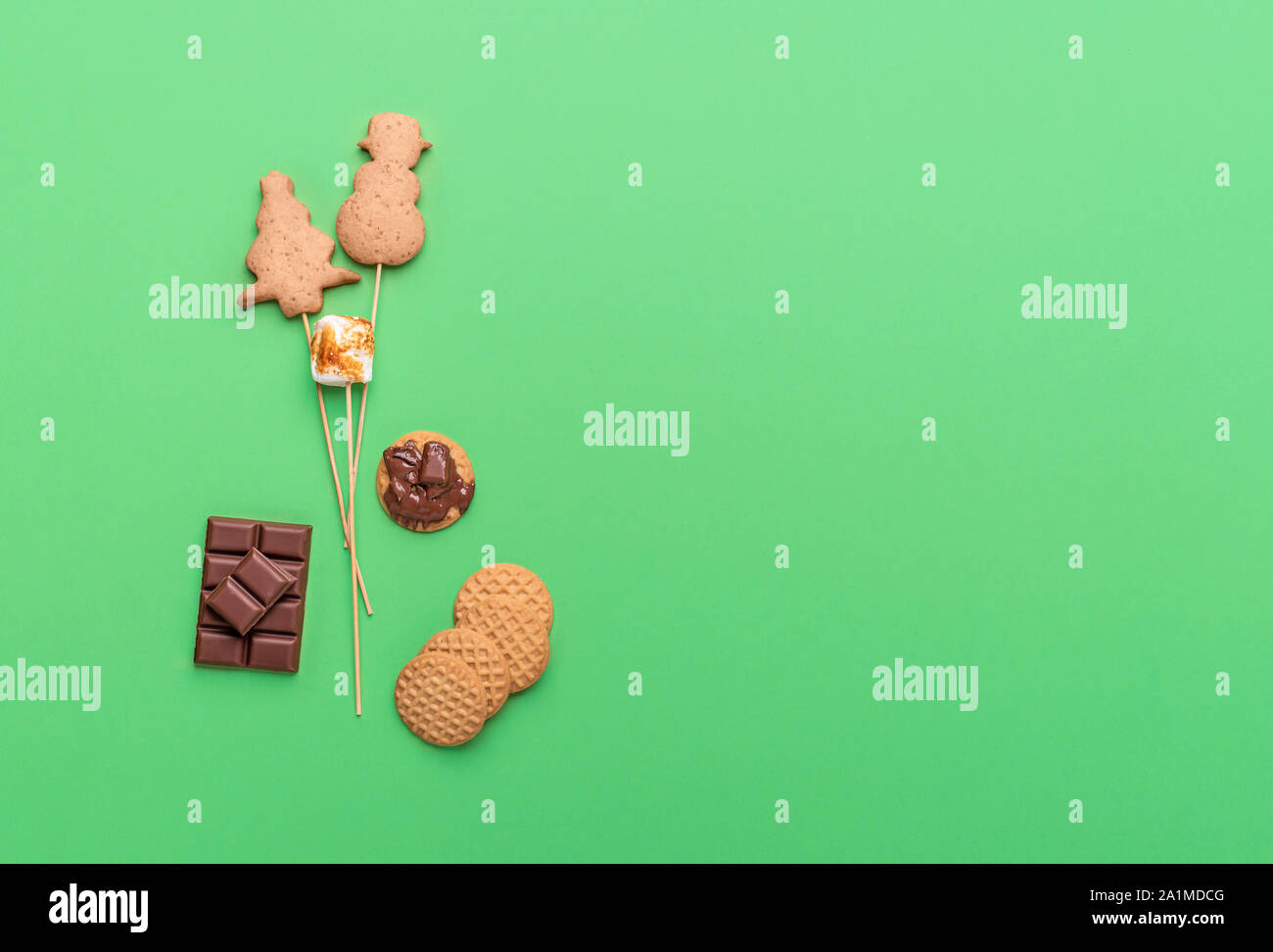Albero di natale di cookie e pupazzo di neve su bastoni con marshmallow e cioccolato fuso, su uno sfondo verde. Al di sopra di vista della tradizionale torta di Natale pop. Foto Stock